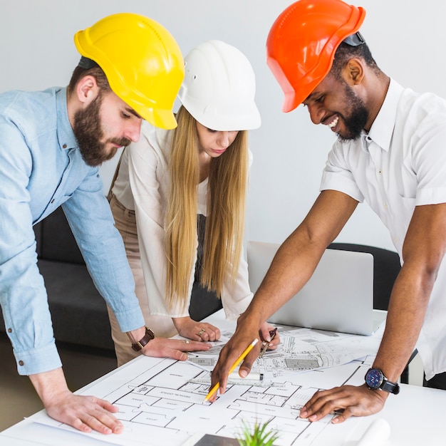 Free photo group of architect discussing layout plan on blueprint in the office