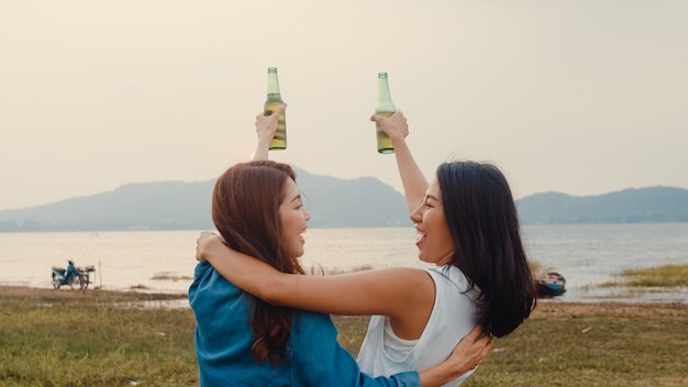 Group of Asia girl couple best friends teenagers drinking have fun salute toast of bottle beer enjoy party with happy moments together in campsite