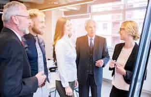 Free photo group of business colleagues looking at young businesswoman giving presentation