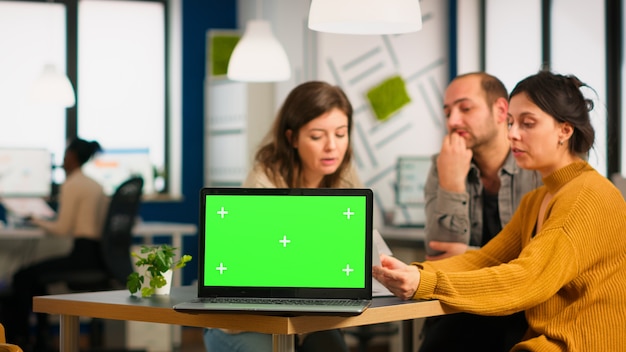 Free Photo group of business people discussing company plan with mockup laptop in front of camera, pc ready for financial project presentation placed on desk. leader using green screen pc with chroma key display