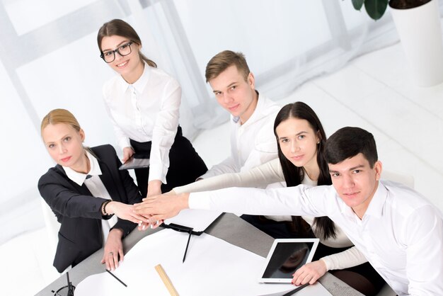 Group of business people stacking each other's hand over the desk