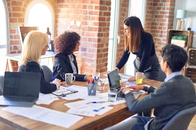 Free Photo group of business workers smiling happy and confident working together with smile on face young beautiful woman standing explaining documents at the office