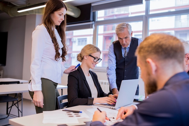 Group of businesspeople looking at laptop in the meeting