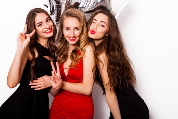 group of celebrating  friends posing in studio. Three pretty woman have fun, winking  ,laughing  and looking at camera.