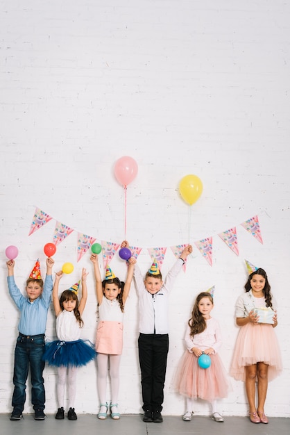 Free photo group of children standing against wall enjoying the birthday party