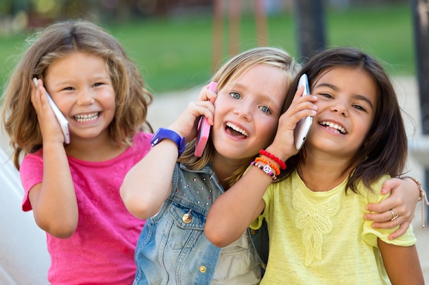 Free photo group of childrens using mobile phones in the park.