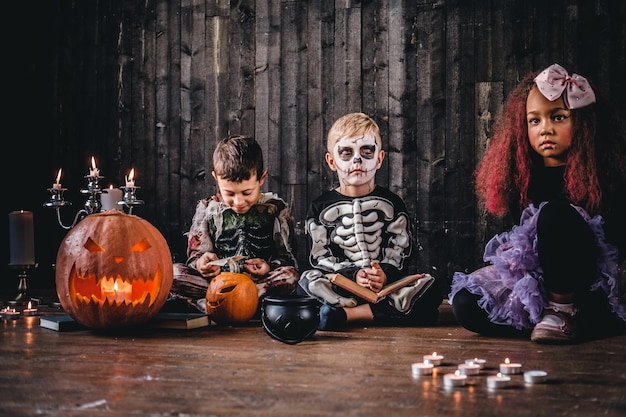 Group of cute multiracial kids in scary costumes during Halloween party in an old house. Halloween concept.