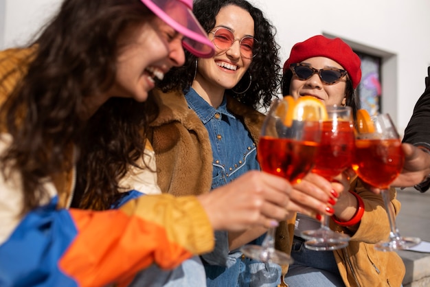 Group of female friends enjoying a glass of aperol spritz outdoors