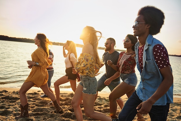 Group of fiends running on beach at sunset