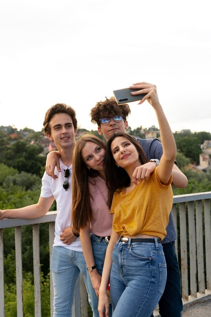 Group of four friends spending time together outdoors and taking selfie