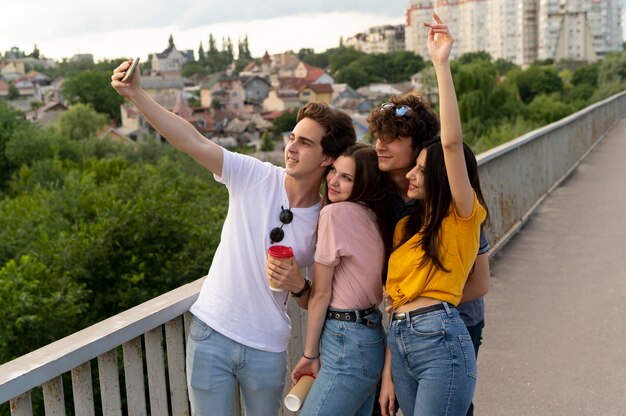 Group of four friends spending time together outdoors and taking selfie