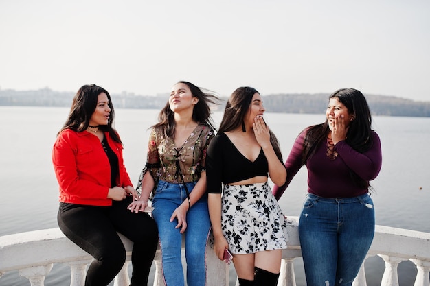 Group of four happy and pretty latino girls from Ecuador posed against lake side