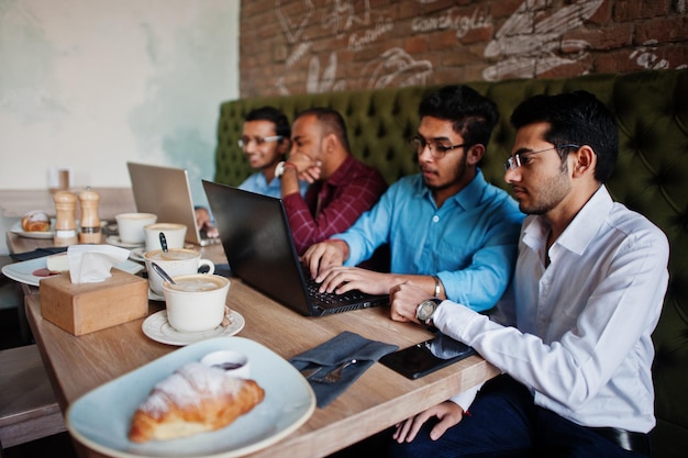 Free Photo group of four south asian men's posed at business meeting in cafe indians work with laptops together using various gadgets having conversation