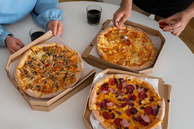 Free photo group of friends eating pizza at home together