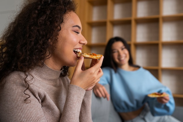 Group of friends eating pizza together at home