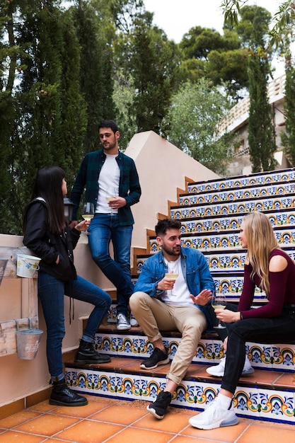 Free Photo group of friends enjoying drinks on staircase