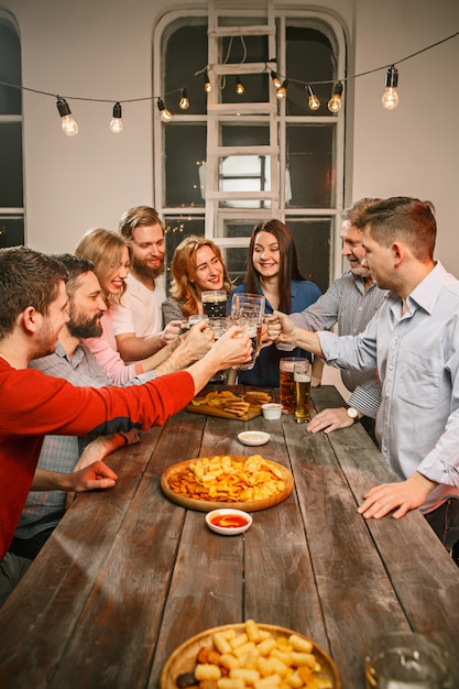 Group of friends enjoying evening drinks with beer on wooden table