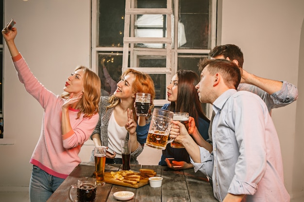 Group of friends enjoying evening drinks with beer on wooden table