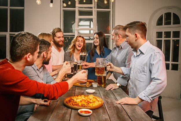 Group of friends enjoying evening drinks with beer on wooden table