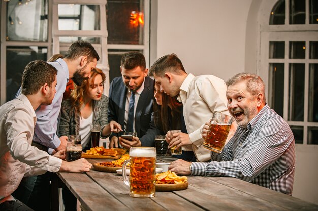 Group of friends enjoying evening drinks with beer on wooden table