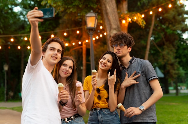 Group of friends having ice cream outdoors and taking selfie