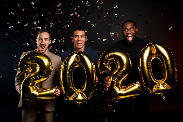 Free photo group of friends holding balloons at new years party