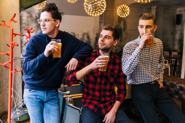 Group of friends holding the beer glasses looking away