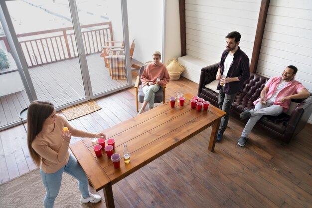 Group of friends playing beer pong together at a party