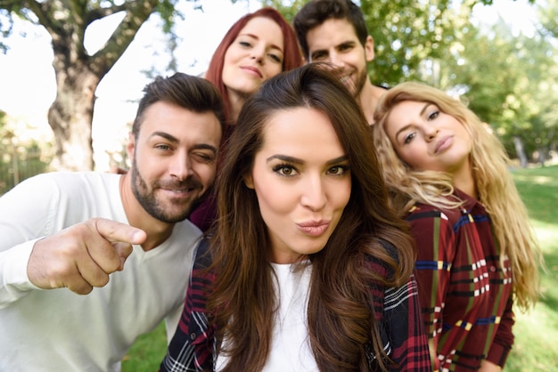 Group of friends in a selfie with a girl in the middle putting kiss face