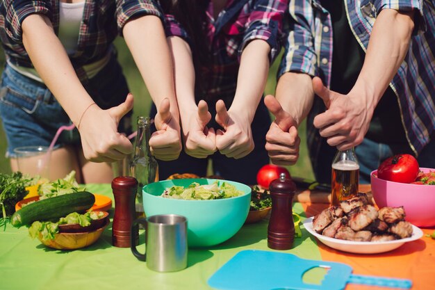 Group of friends showing thumbs up to table of food.