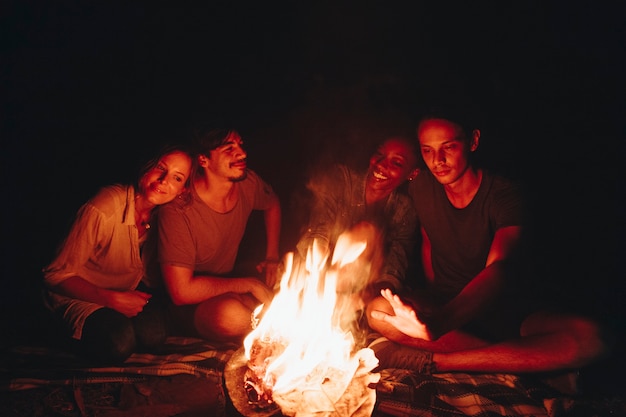 Free photo group of friends sitting around a bonfire at a campsite