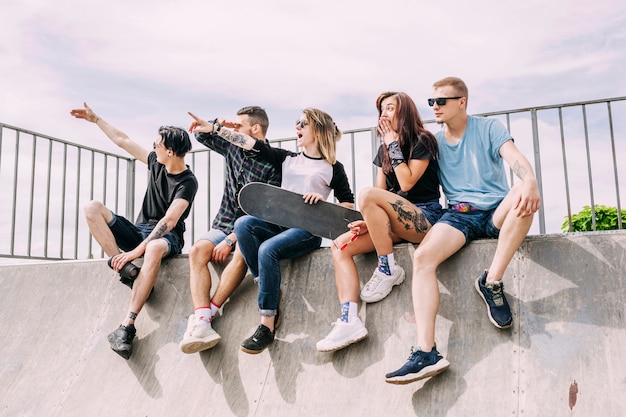 Free photo group of friends sitting on ramp pointing at something