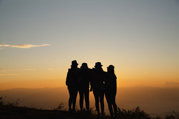 Group of friends standing together on greensward and enjoying themselves. 