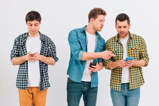 Group of friends using mobile phone against white backdrop