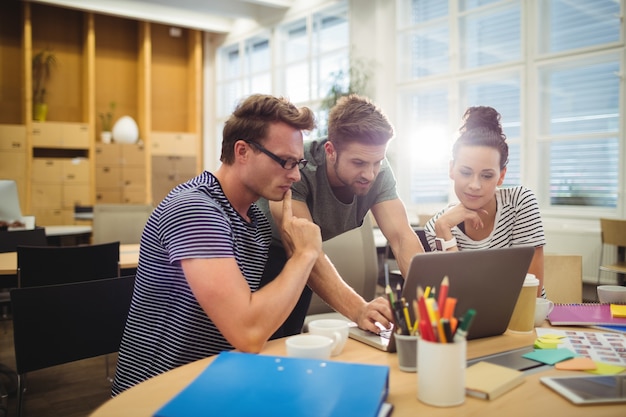 Free photo group of graphic designers discussing over laptop at their desk