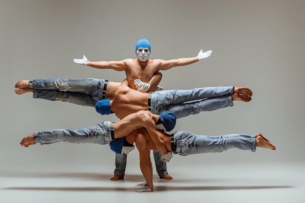 Free photo the group of gymnastic acrobatic caucasian men on balance pose