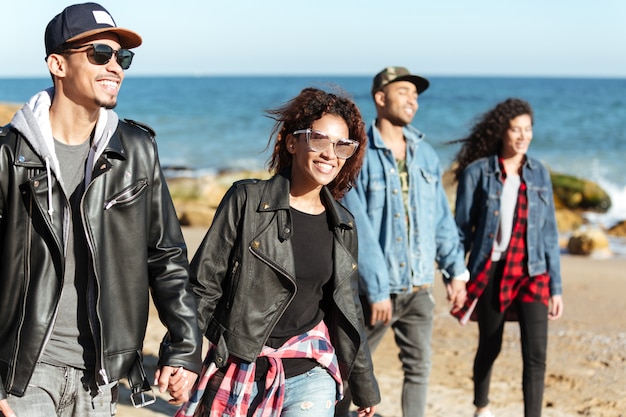 Group of happy african friends walking outdoors at beach.