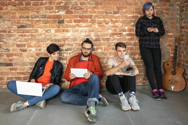 Group of happy caucasian young people behind the brick wall.