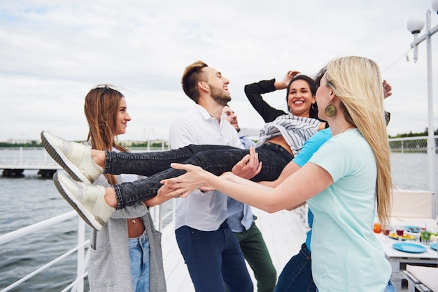 Free Photo group of happy friends at the beach, man tossing a happy woman.