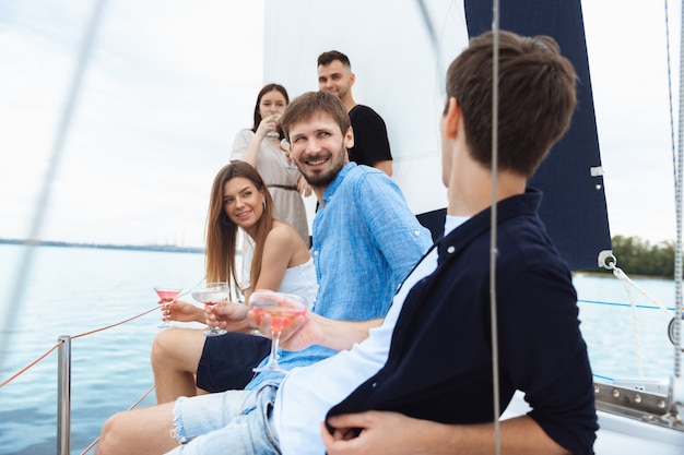 Free Photo group of happy friends drinking vodka cocktails at boat party outdoor, summer