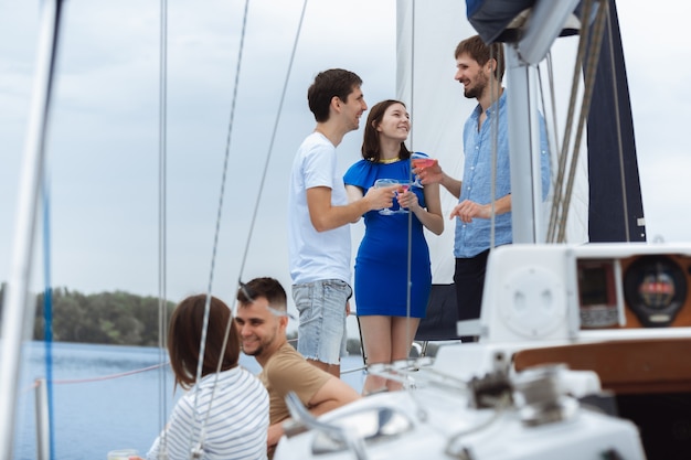 Group of happy friends drinking vodka cocktails at boat party outdoor, summer