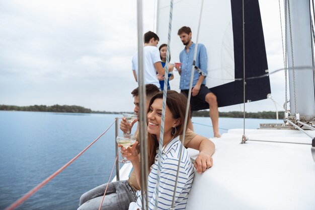 Group of happy friends drinking vodka cocktails at boat party outdoor, summer