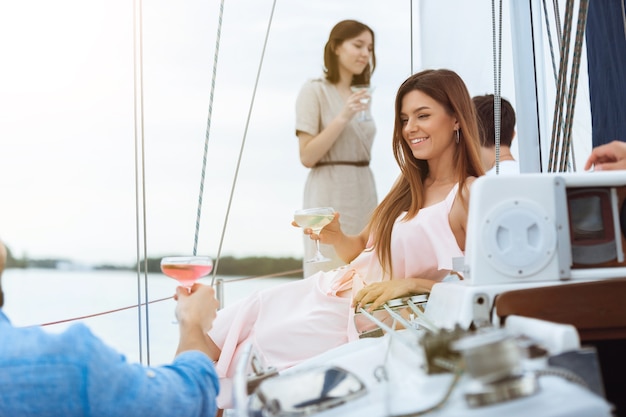 Group of happy friends drinking vodka cocktails at boat party outdoor, summer