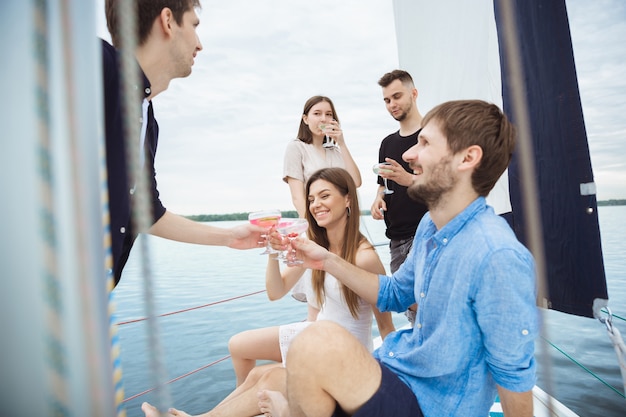 Free photo group of happy friends drinking vodka cocktails in a boat