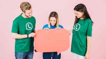 Free photo group of happy friends holding empty orange speech bubble