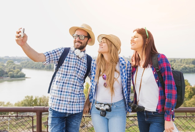 Group of happy friends taking selfie on cellphone at outdoors