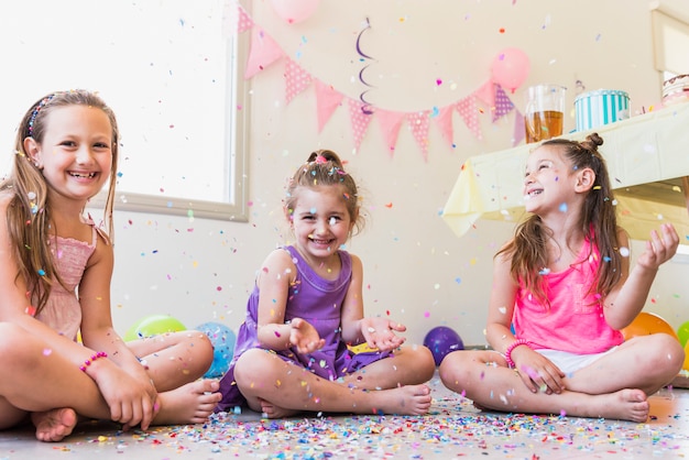 Free photo group of happy girls playing with confetti during birthday party