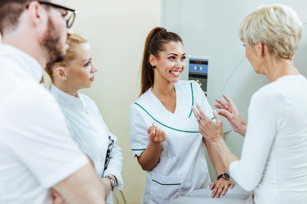 Group of happy healthcare workers talking with mature patient before MRI scan procedure in the hospital Focus is on happy nurse