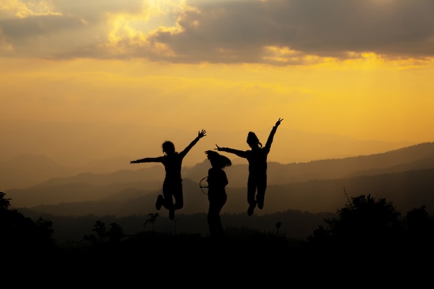 Free photo group of happy people jumping in the mountain at sunset