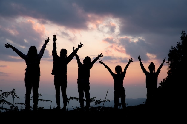 Group of happy people playing at summer sunset in nature